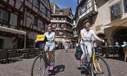Zwei Radlerinnen genießen die Fahrt durch die Altstadt Colmars.