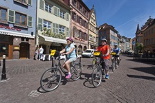 Drei Radler fahren durch die Altstadt von Colmar.