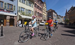 Drei Radler fahren durch die Altstadt von Colmar.