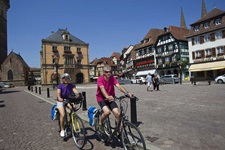 Ein Radlerpärchen überquert den Marktplatz (Place du Marché) von Obernai.