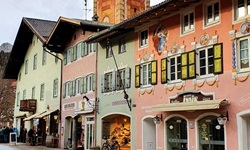 Bunte Häuserfassaden in MIttenwald werden vom Turm der Kirche St. Peter und Paul überragt.