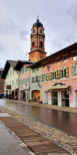 Bunte Häuserfassaden in MIttenwald werden vom Turm der Kirche St. Peter und Paul überragt.