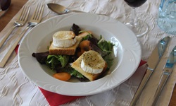 Zwei mit Weichkäse überbackene Toastscheiben auf einem Bett aus Blattsalat.