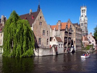 Ein Boot im Wasserkanal fährt an der mittelalterlichen Stadt Brügge in Belgien mit gotischen Häusern vorbei