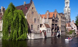 Ein Boot im Wasserkanal fährt an der mittelalterlichen Stadt Brügge in Belgien mit gotischen Häusern vorbei