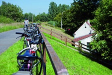 Fahrräder auf einem Deich lehnen an Holzgeländer in Flandern, Belgien