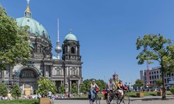 Drei Fahrradfahrer fahren vom Berliner Dom weg