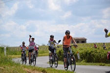 Eine Gruppe Radlerinnen fährt auf einem asphaltierten Radweg an den Weinreben des Bordeauxgebiets entlang.