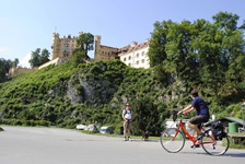 Ein Fahrradfahrer und ein Wanderer mit Hund auf dem Weg zum Schloss Hohenschwangau