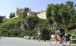Ein Fahrradfahrer und ein Wanderer mit Hund auf dem Weg zum Schloss Hohenschwangau