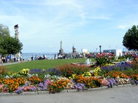 Parkanlage in Konstanz mit wunderschönen Blumenbeeten und einem Springbrunnen - im Hintergrund ist der Hafen mit der Imperia zu erkennen