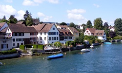 Blick auf eine Häuserreihe am Bodensee mit jeweils einem anglegten Boot