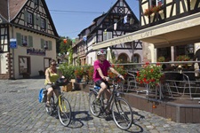 Zwei Fahrradfahrer fahren durch die französische Gemeinde Börsch an einem Café vorbei