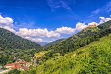 Blick auf ein Dorf mit Weinbergen und einer hoch thronenden Burg auf der Radreise an der Elsässischen Weinstraße und durch den Breisgau