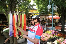 Eine Radlerin bummelt über einen ungarischen Markt und begutachtet die an einem Stand angebotenen bunten Schals.