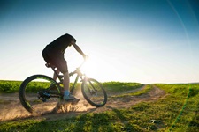 Ein Mountainbiker fährt auf einem sandigem Weg in eine scharfe Kurve