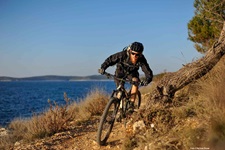 Ein Mountainbiker fährt einen Trail an einer Steilküste in Kroatien entlang