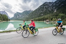 Drei Radfahrer radeln an einem See bei der Radreise von den Dolomiten nach Venedig vorbei