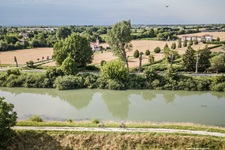 Zwei Radfahrer radeln neben einem Fluss in typischer Landschaft von Italien entlang