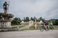 Zwei Radfahrer radeln an der Villa Barbaro und dem davor gelegenen Brunnen nahe Asolo vorbei