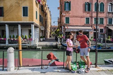 Eine Frau und ein Mann in Venedig lehnen sich an einen Zaun neben dem Gewässer von Venedig und begutachten ein Prospekt