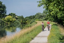 Zwei Radfahrer auf einem Radweg neben einem Fluss