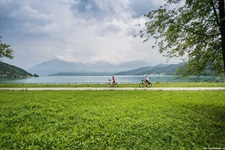 Zwei Radfahrer auf dem Radweg an einem See auf dem Weg von den Dolomiten nach Venedig