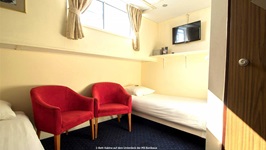 Eine 2-Bett-Kabine auf dem Unterdeck der MS Bordeaux mit zwei gemütlichen roten Sesseln.