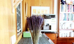 Detailansicht des Restaurants auf der Caprice: Eine Vase mit Lavendel steht auf einem Sideboard, im Hintergrund sind die Cafémaschine und das Bücherregal zu erkennen