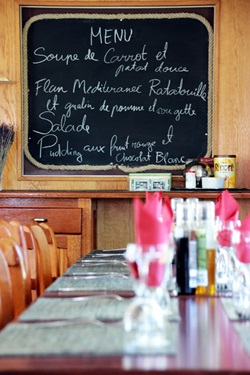 Blick über den eingedeckten Tisch zur Menütafel auf der Caprice