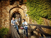 Ein Radlerpärchen steht auf der Brücke der Burg Thurgant und studiert eine Infobroschüre.