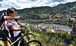 Ein Radlerpärchen schaut vom gegenüberliegenden Moselufer auf Cochem.
