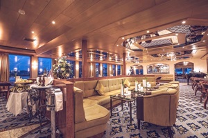 Blick zur gemütlichen Lounge mit Sesseln und großer Bank im Saloon der MS Swiss Crown