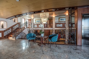 Das mit zwei blauen Sesseln und einem Tisch mit Orchidee eingerichtete Treppenhaus der MS Swiss Crown