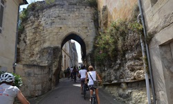 Eine Radlergruppe durchquert auf dem Weg von Bourg-sur-Gironde nach Blaye ein steinernes Tor.