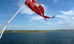 Die dänische Flagge weht am Heck eines Schiffes im Fahrtwind.