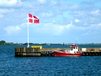 Hafenidyll mit dänischer Flagge und einem kleinen Motorschiff.