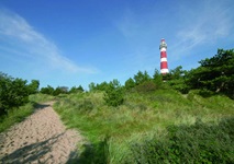 Ein Sandweg zu einem rot-weiß gestreiften Leuchtturm auf der Insel Ameland