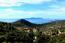 Wunderschöner Blick über einen Teil der Insel Hvar und das sie umgebende Meer. In der Bildmitte befindet sich ein kleiner Ort, dessen Häuser sich um die Kirche scharen.