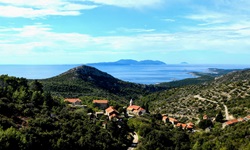 Wunderschöner Blick über einen Teil der Insel Hvar und das sie umgebende Meer. In der Bildmitte befindet sich ein kleiner Ort, dessen Häuser sich um die Kirche scharen.