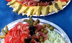 Platten mit Essen: Käse, Gewürzgurken, Oliven, Schinken, Gemüsegurken und Tomaten