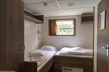 Blick in eine 2-Bett-Kabine mit 2 ebenerdig versetzt stehenden Betten auf der MS De Nassau.