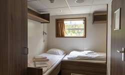 Blick in eine 2-Bett-Kabine mit 2 ebenerdig versetzt stehenden Betten auf der MS De Nassau.
