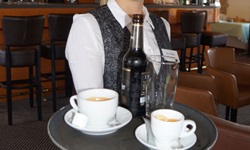 Eine Kellnerin der MS De Willemstad mit einem voll beladenen Tablett, afu dem Kaffee und eine Bierflasche stehen.