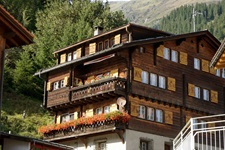 Blick auf ein typisches mit Holz verkleidetes Haus und geschmückten Balkonen der Schweiz in Disentis