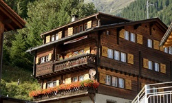 Blick auf ein typisches mit Holz verkleidetes Haus und geschmückten Balkonen der Schweiz in Disentis