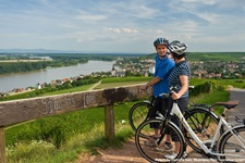 Zwei Radler in Rheinland-Pfalz machen eine Pause am Aussichtspunkt Schauinsland und blicken auf den Rhein