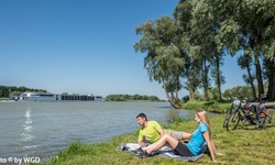 Ein Pärchen macht am Donauufer Pause und schaut auf den Fluss.
