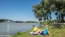 Ein Pärchen macht am Donauufer Pause und schaut auf den Fluss.