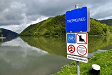 Ein blaues Schild am Ufer der Donau weist auf den Treppelweg (= Treidelpfad) hin, auf dem der Donauradweg zwischen Passau und Wien in großen Teilen verläuft.
